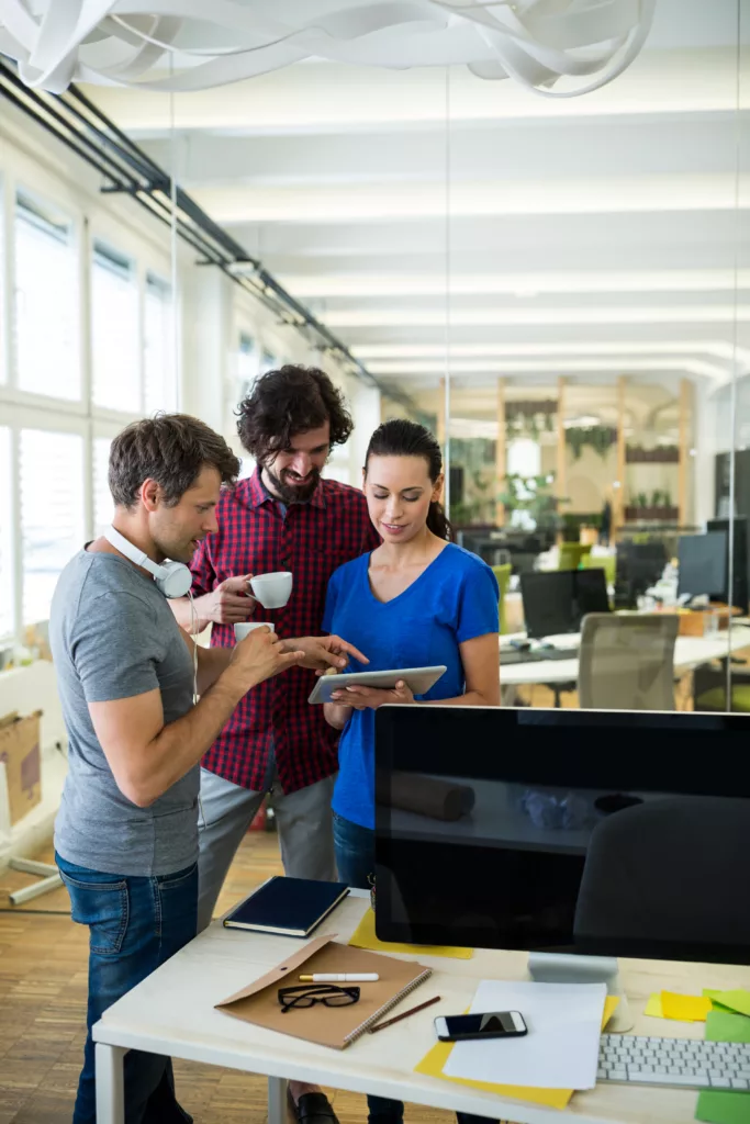 Group of graphics designers using digital tablet while having coffee